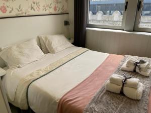 um quarto com uma cama grande e toalhas em Liber Guest House em Braga