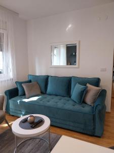 een woonkamer met een blauwe bank en een tafel bij Apartman Korać in Vrnjačka Banja