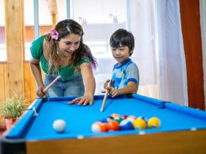 a woman and a young boy playing pool at Tupa Hotel in Hanga Roa