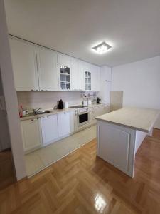 a large kitchen with white cabinets and a wooden floor at Luxury Central Apartment in Strumica