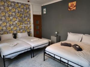two twin beds in a room with a floral wall at Tulip Hotel Blackpool in Blackpool