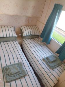 two beds in a small room with a window at Idyllic Family Holiday Caravan in Skegness