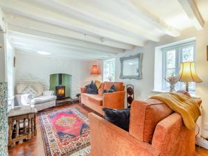 a living room with orange furniture and a fireplace at Church House Cottage in East Stour