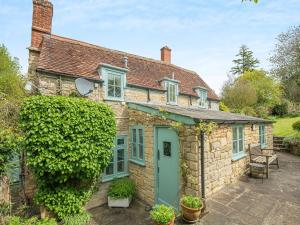 an old stone house with a green door at Church House Cottage in East Stour