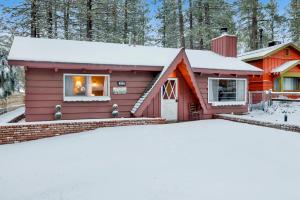 a red house with snow in front of it at Pine Cone Cottage by Big Bear Vacations Adorable Walk To Lake Furnished Chalet in Big Bear Lake