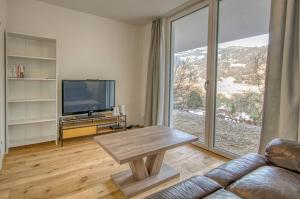 a living room with a couch and a table and a tv at Chalet Lake View - by Alpen Apartments in Zell am See