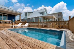 a swimming pool with a wooden deck and a house at Sunny & 75 in Dauphin Island