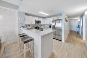 a kitchen with white cabinets and a counter with stools at Calypso 3 Luxury Beach Vacation Sleeps 8 in Panama City Beach