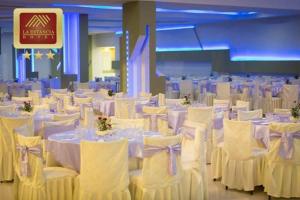 un salón de banquetes con mesas blancas y sillas blancas en La Estancia Hotel, en Huánuco