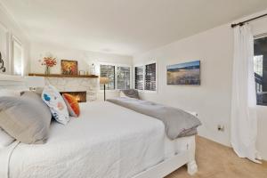 a white bedroom with two beds and a fireplace at Soaring Pines by Big Bear Vacations Central Cozy Estate Chalet in Big Bear Lake
