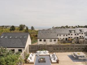 un patio con sofás y mesas en una terraza de madera en Nyth Y Fran en Abersoch