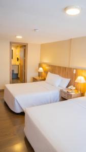 a hotel room with two beds and two lamps at Fenix Hotel in Quito