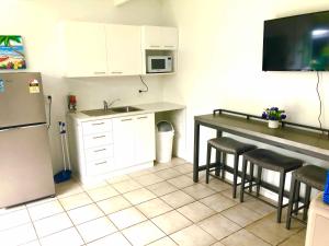 a kitchen with a refrigerator and a table with stools at Avarua Escape, Rarotonga in Avarua