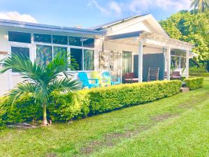 a house with a palm tree in the yard at Avarua Escape, Rarotonga in Avarua
