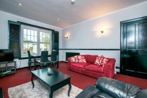 Cosy & Central 2BD Apartment Milngavie, Glasgow في ميلنغافي: غرفة معيشة مع أريكة حمراء وطاولة