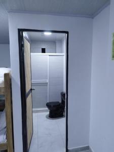 a bathroom with a toilet and a door to a room at Apartamentos Vistas del Caribe Sede Campestre in Cartagena de Indias
