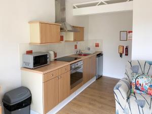 a kitchen with wooden cabinets and a microwave and a couch at Cloverleaf in Saltfleetby Saint Clement