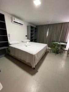 a bedroom with a large white bed and a table at Get One in Tambaú