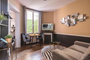 a living room with a couch and a table at MM Suites Reims Centre Terasse in Reims