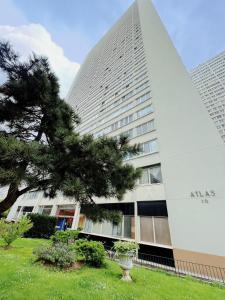 un edificio alto con un árbol delante de él en Apartment near subway and supermarket en París