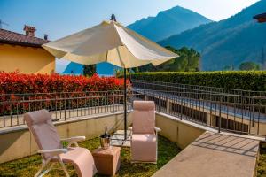 a patio with two chairs and an umbrella at Happy Guest Apartments - Lake & Relax in Riva di Solto