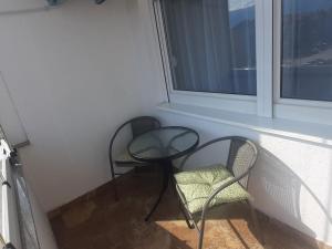 2 chaises et une table devant une fenêtre dans l'établissement Apartman Stella Istočno Sarajevo, à Lukavica