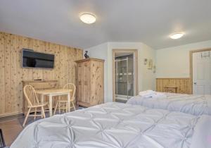 a bedroom with two beds and a table and a tv at Hébergement chez le D in Saint Zenon