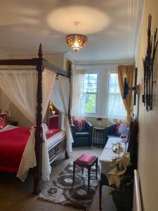 a bedroom with a canopy bed and a couch at The Palms Guest house in Torquay