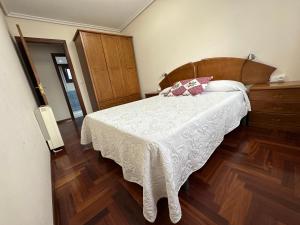 sypialnia z białym łóżkiem z drewnianym zagłówkiem w obiekcie Apartamento Salgueirón w mieście Cangas de Morrazo