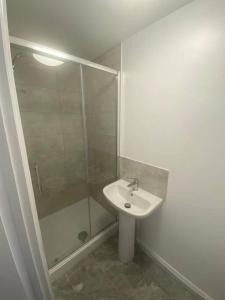 uma casa de banho branca com um lavatório e um chuveiro em Guest House in Milton Keynes em Milton Keynes