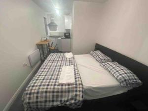um pequeno quarto com uma cama com um cobertor xadrez em Guest House in Milton Keynes em Milton Keynes