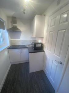 a small kitchen with a white door and a microwave at Guest House in Milton Keynes in Milton Keynes