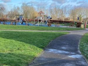 um caminho num parque com um parque infantil em Guest House in Milton Keynes em Milton Keynes