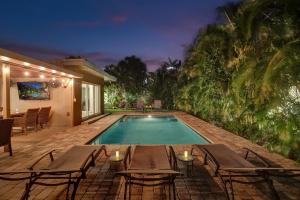 a swimming pool with tables and chairs next to a house at Windward Escape in Fort Lauderdale