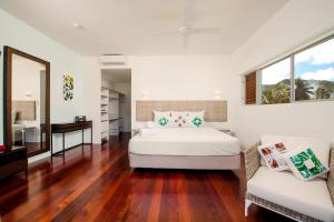 een witte slaapkamer met een bed en een bank bij Crystal Blue Lagoon Villas in Rarotonga