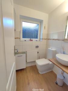 ein Bad mit einem Waschbecken, einem WC und einem Fenster in der Unterkunft Nordseehaus Husum mit Fahrrädern in Husum