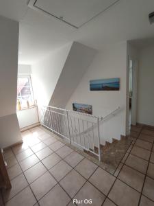eine Treppe in einem Zimmer mit weißen Wänden und Fliesenböden in der Unterkunft Nordseehaus Husum mit Fahrrädern in Husum