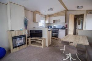 a small kitchen with a table and a television in it at Lovely 4 Berth Holiday Home At Felixstowe Beach Holiday Park Ref 55008yc in Walton