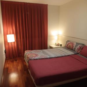 Habitación de hotel con cama y cortina roja en Bcn apartments, en Hospitalet de Llobregat