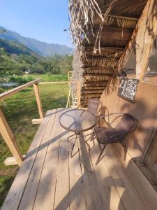 een terras met een tafel en stoelen bij Pachamaya River Hostel in Lanquín