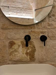 eine Steinmauer mit einem Waschbecken und einem Spiegel in der Unterkunft BORGANTHIA - IL CHIOSTRO DEI MEDICI in Alberobello