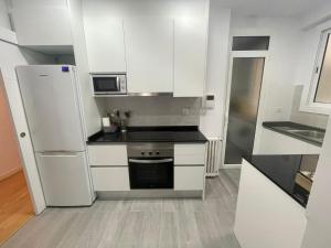 a small kitchen with white cabinets and a refrigerator at Mistral Barcelona Centro in Barcelona