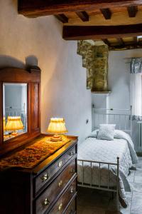 a bedroom with a dresser and a bed with a mirror at La Casetta Nel Borgo in Castelnuovo di Val di Cecina