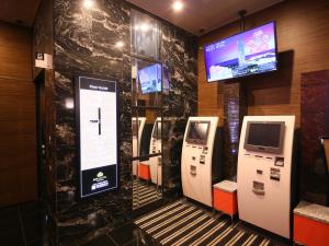 baño con 3 teléfonos de pago y TV en APA Hotel Tsukiji-eki Minami, en Tokio