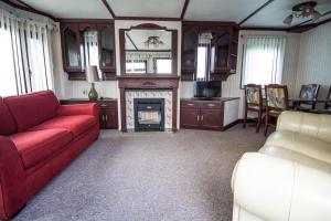 a living room with a red couch and a fireplace at Dog Friendly 6 Berth Static Caravan By The Beach In Hunstanton Ref 13008l in Hunstanton