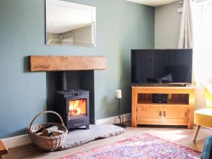 a living room with a fireplace and a tv at Lords Cottage in Coleford