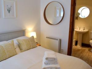 een slaapkamer met een bed met een wastafel en een spiegel bij Wheatsheaf Cottage - 80021 in Sawdon