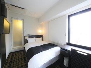 東京にあるアパホテル〈築地駅南〉のベッドと窓が備わるホテルルーム