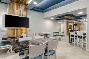 a dining room with a table and chairs and a flat screen tv at Clarion Pointe Tampa-Brandon Near Fairgrounds and Casino in Tampa