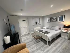 ein Schlafzimmer mit einem Bett und einem Stuhl darin in der Unterkunft Luxury Detached Studio Apartment - Free Super Fast WiFi - Free Parking - 15 Mins from Luton Airport in Luton